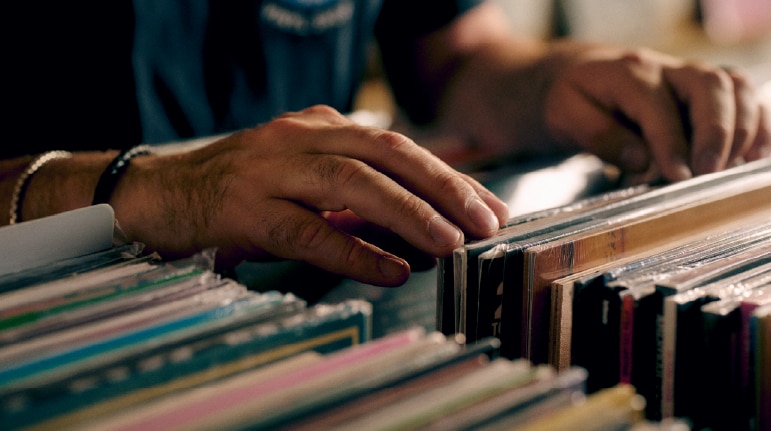Record store owner holding vinyl records in a shop