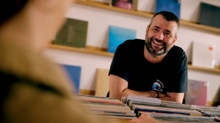 Record store owner holding vinyl records in a shop