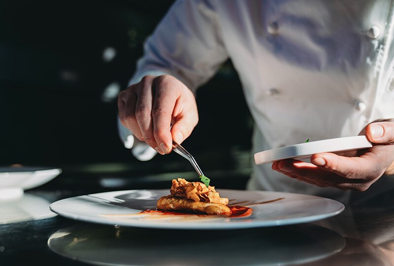 Chef carefully plating a gourmet dish in a fine dining restaurant.