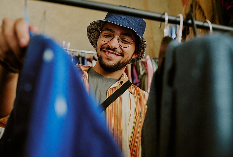 Man browsing clothes at a local market, smiling while shopping.