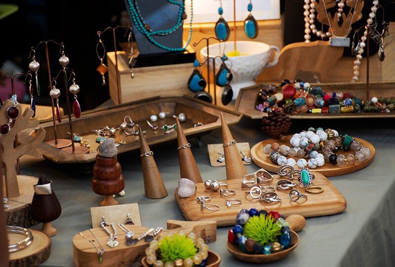 Handcrafted jewellery display with rings, earrings, and beaded necklaces on wooden stands.