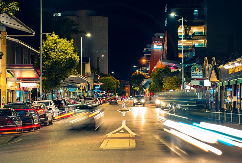 Night view of Darwin city street with cars, lights, and people enjoying the lively nightlife.