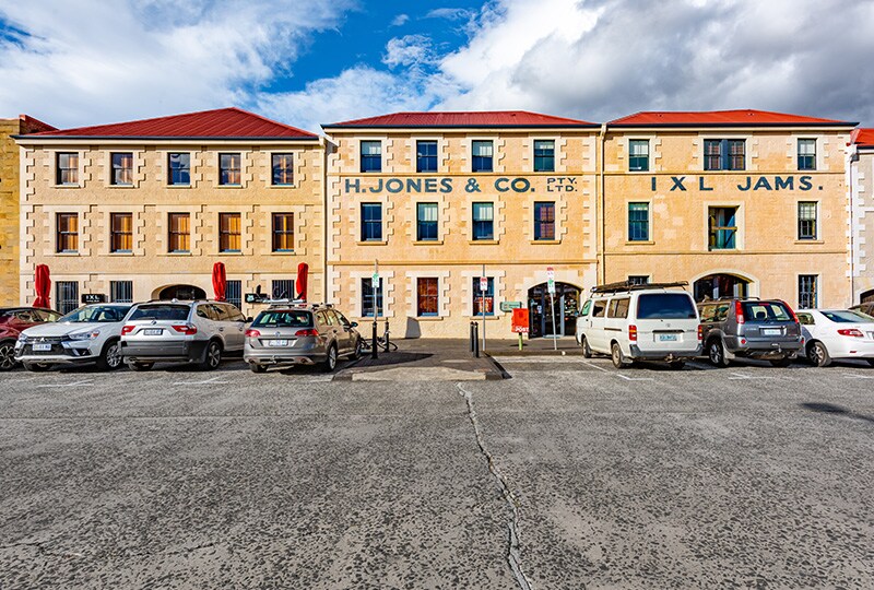 H. Jones & Co. sandstone building with red-roof heritage architecture and parked cars in Hobart.