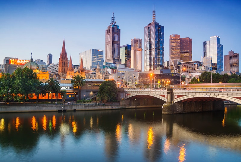 Melbourne city skyline and Princes Bridge reflected in the Yarra River at dusk.