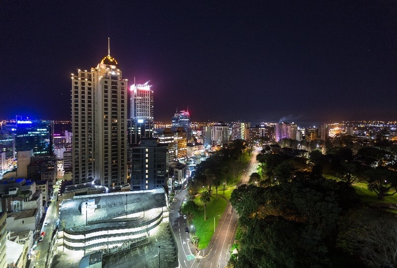 Melbourne skyline illuminated at night with city lights and tree-lined streets.