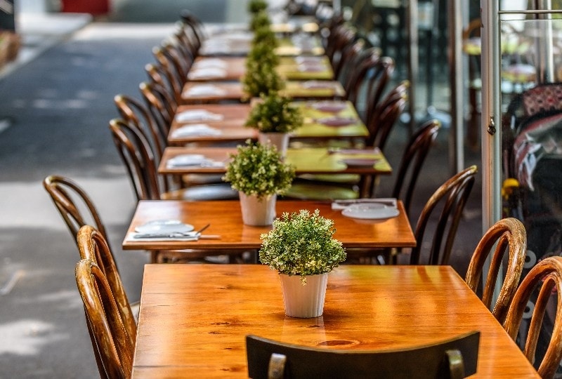 Row of neatly set wooden tables at an outdoor café in Melbourne’s laneways.