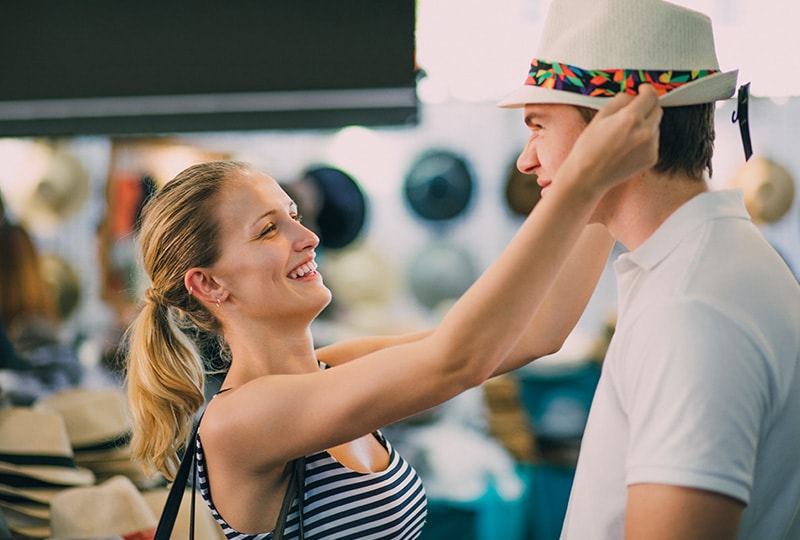 Woman placing a hat on a man’s head while shopping at a local Melbourne market.