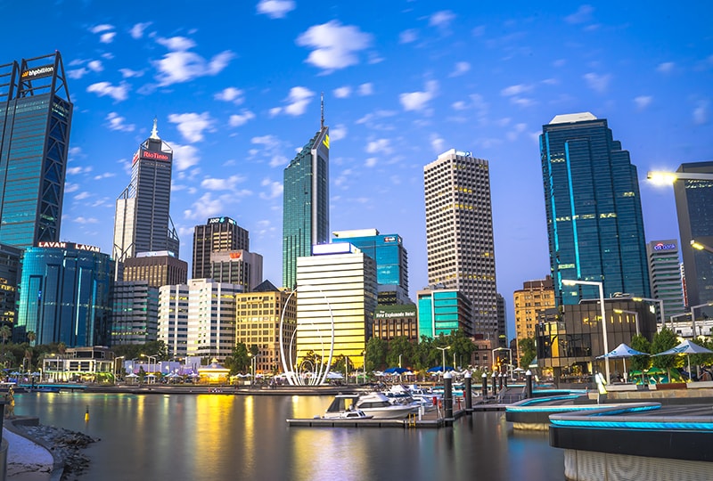 Perth city skyline with modern skyscrapers reflecting in Elizabeth Quay at dusk.