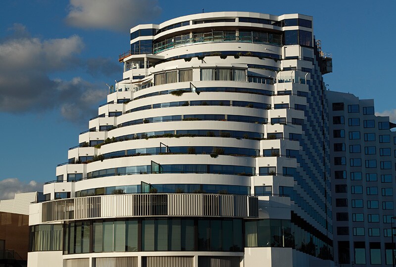 Contemporary tiered glass hotel building under a blue sky in Perth.