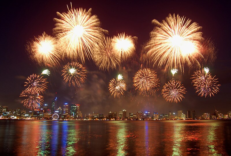 Spectacular fireworks display lighting up the Perth city skyline over the Swan River at night.