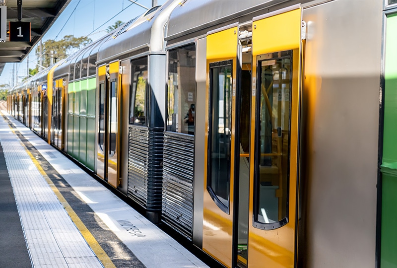 Sydney suburban train stopped at a platform with yellow doors open.