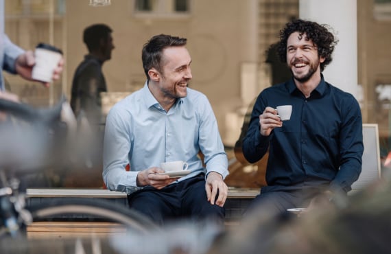 Two men laughing while drinking coffee