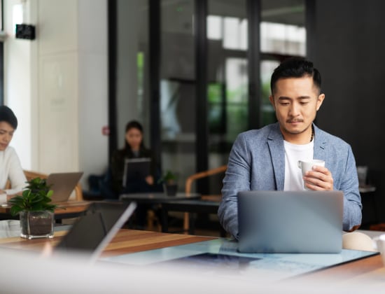 Man drinking coffee on laptop