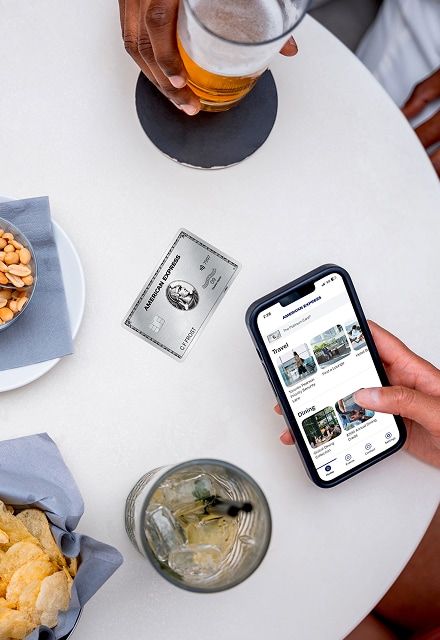 Overhead shot of table with food, and  a phone with the Amex Experiences App open    