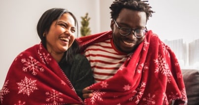 Two people wrapped in a warm blanket.