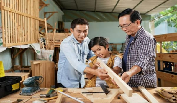 Two men guiding a child to do carpentry work
