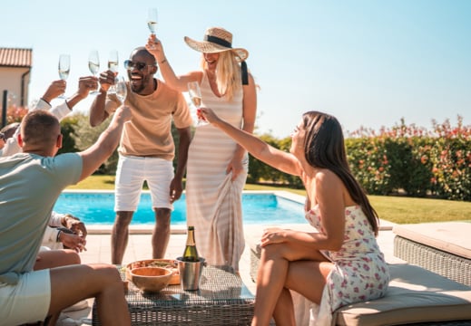 Group of travellers toasting by a pool.