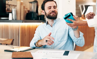 Businessperson tapping their phone on a payment terminal.
