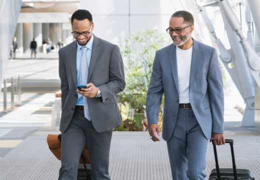 Two people walking with luggage. 