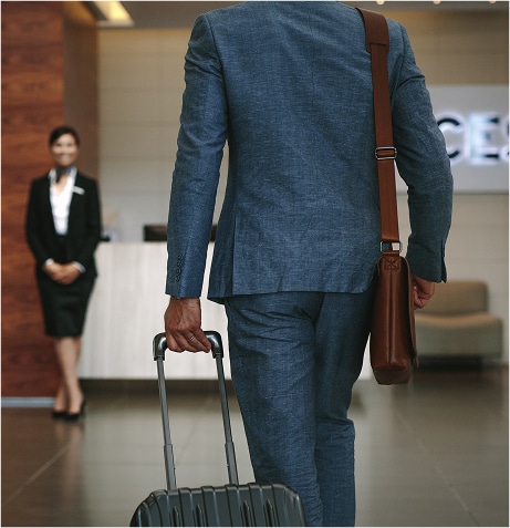 A person in a suit carrying a suitcase
