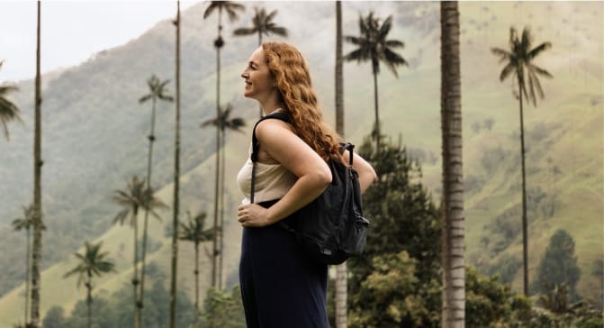 A person with a backpack standing in front of palm trees