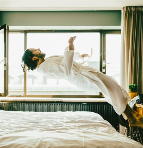 A person in a robe jumping on a bed