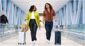 A person and person walking with luggage
