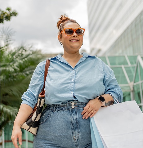 A person wearing sunglasses and holding shopping bags