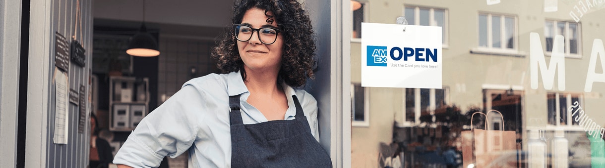 Small business owner standing in storefront with OPEN sign in window