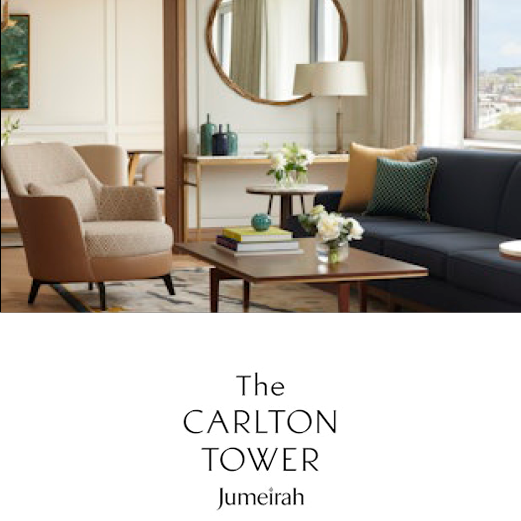 The Carlton Tower, Jumeirah. A modern and contemporary lounge at Carlton Tower. A large circular mirrow hangs on the far wall. Chic furniture fills the lounge and sunlight fills the room from a large window.