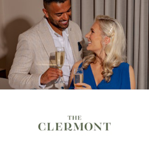 The Clermont. A smiling and happy couple look into each others eyes, each holding a glass of champagne.