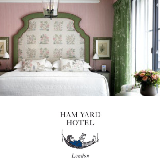 Ham Yard Hotel, London. A luxury hotel room at the Ham Yard Hotel themed in pastel pink and green. Sunlight fills the room from a tall window.