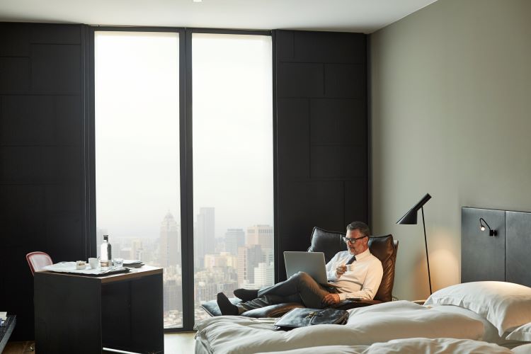 Businessman using laptop while holding coffee cup in hotel room