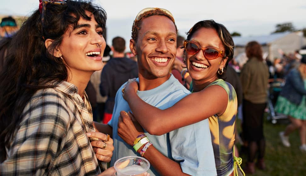 Three people gathered outside in a crowed looking forward