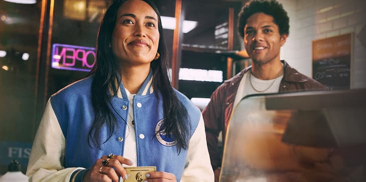 Person paying at restaurant counter with Amex Gold Card