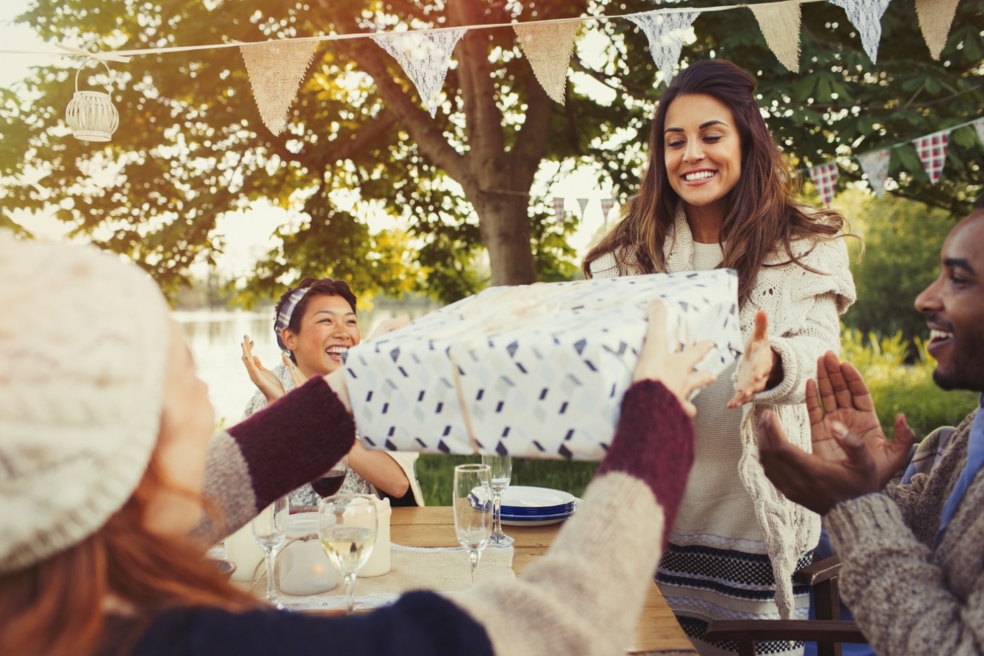 Friends passing presents to each other across table