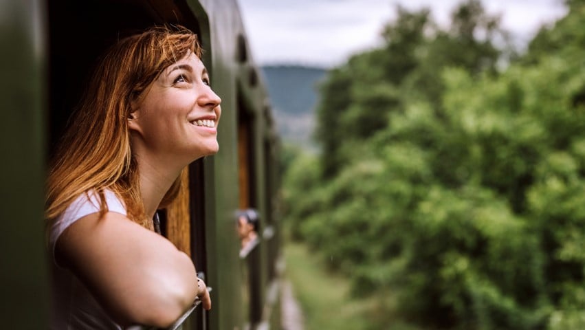 Woman smiles while leaning out of train window