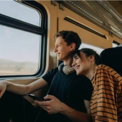 Young couple smiling while looking out of a train window