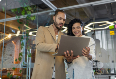 Two colleagues looking at a laptop together smiling