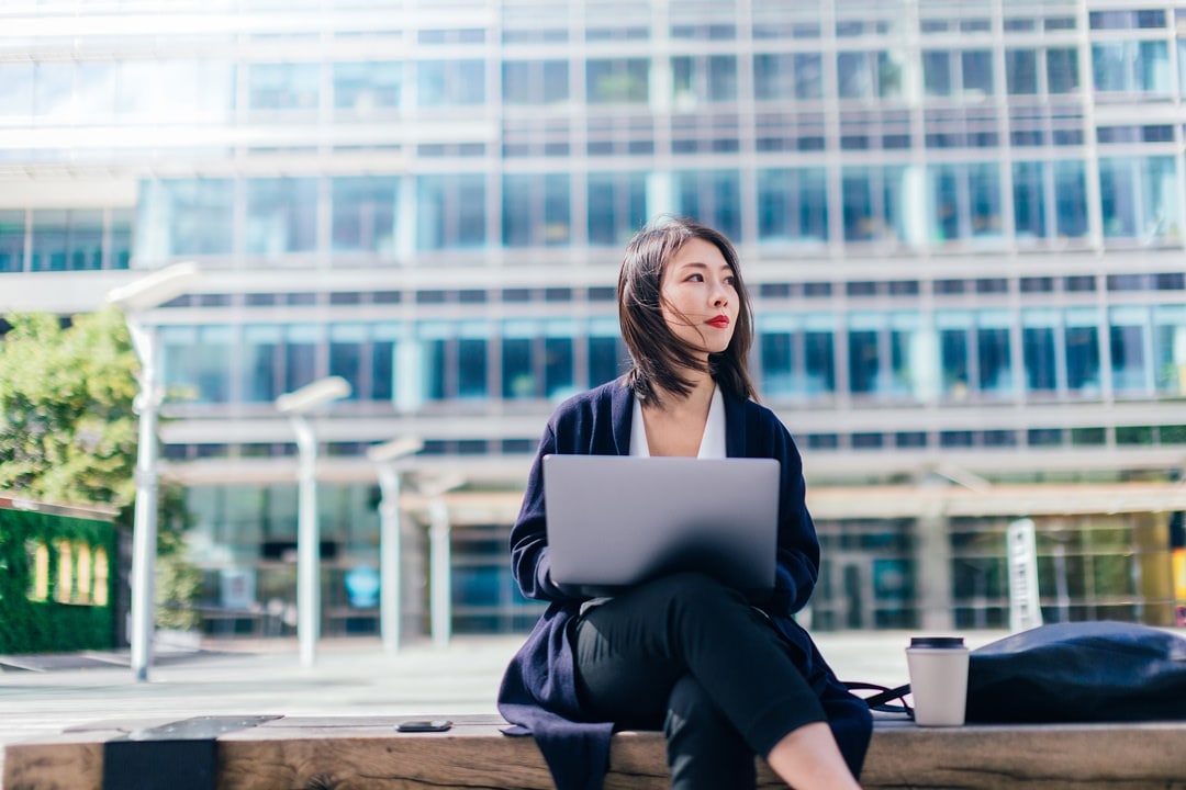 Woman stepping out of a car and holding a smartphone outside an office building