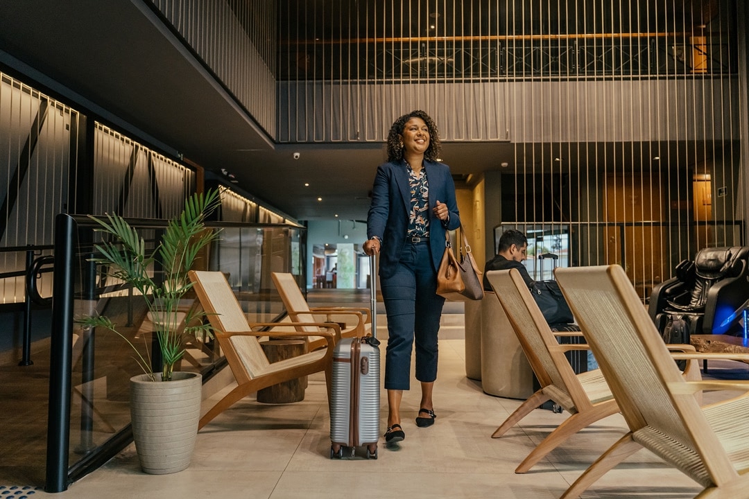 Woman walking through a modern lounge with rolling luggage