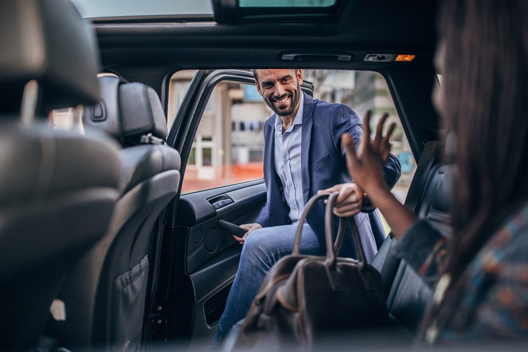 Man getting into a car while holding a bag