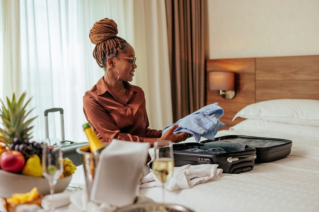 Woman unpacking clothes from a suitcase in a hotel room