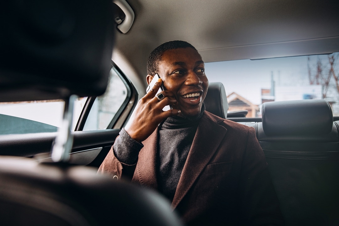 Man in a car using a smartphone and smiling