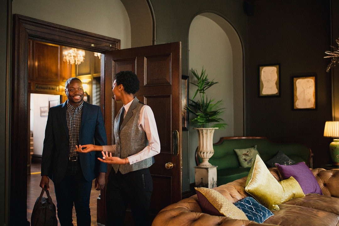 Business traveller arriving at a hotel room with bags, greeted at the door