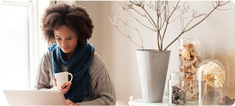 Person sits and looks at laptop while drinking coffee