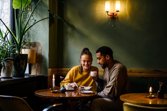 Couple having cappuccinos and cheesecake in coffee shop.