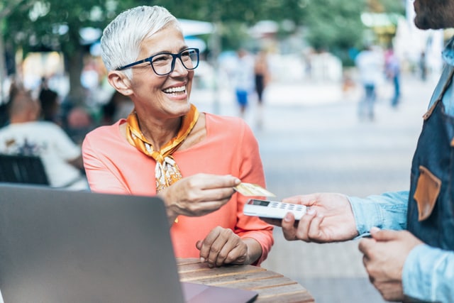 Woman paying contactless in sidewalk cafe.