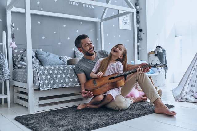 Father teaching his little daughter to play guitar.