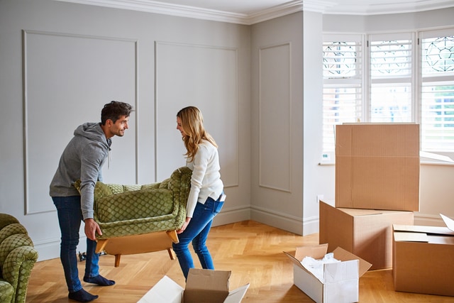 Young couple moving a sofa into their new home.